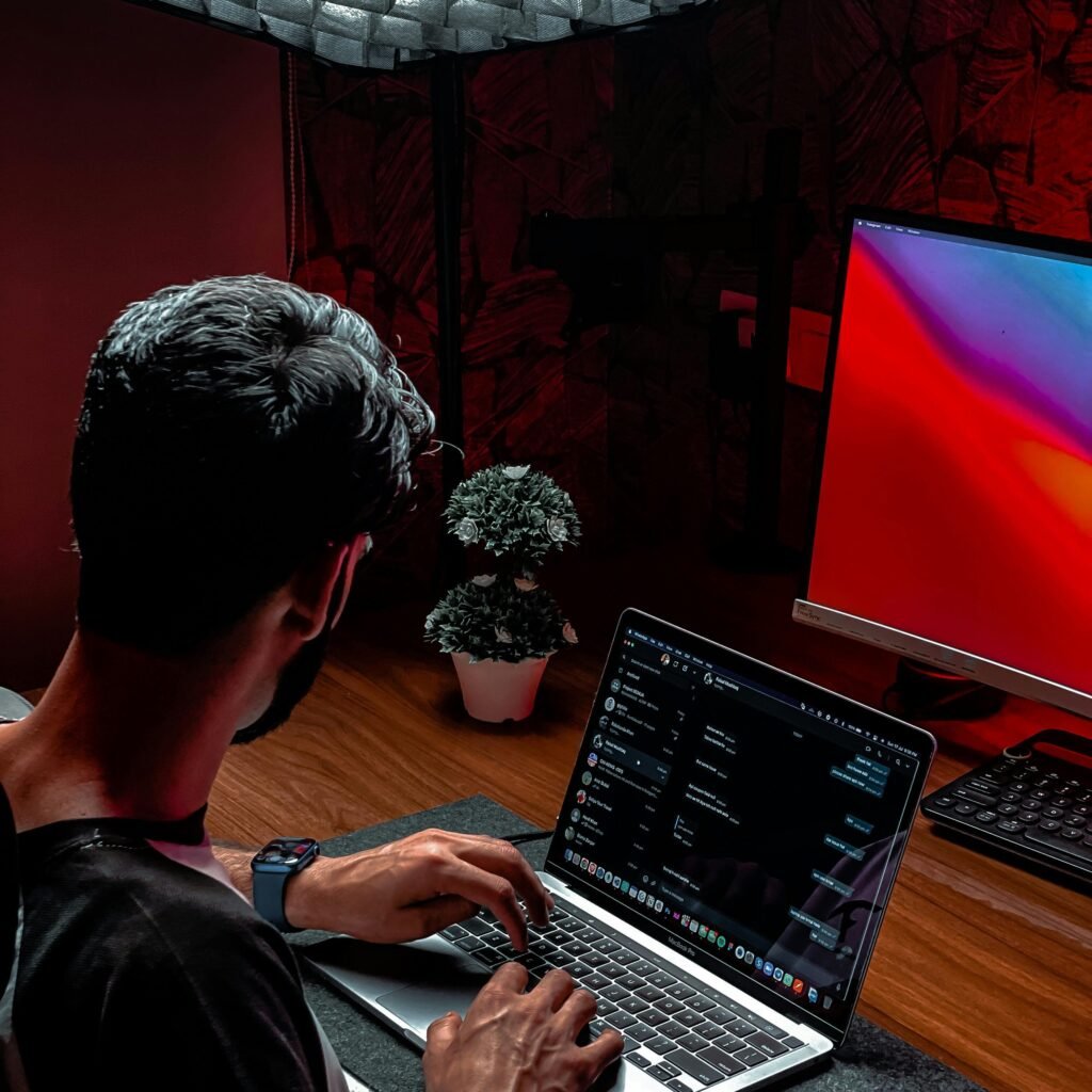 A man working on a laptop in a modern and stylish indoor workspace with ambient lighting.